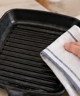 Čistá vroubkovaná grilovací pánev důkladně osušená bílou kuchyňskou utěrkou