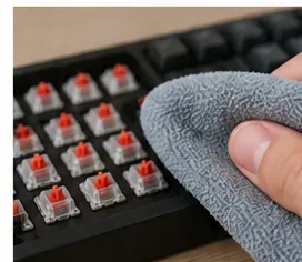 A microfiber cloth wiping the exposed keyboard case around mechanical switches.