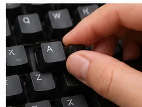 A hand pressing a cleaned black keycap back onto a mechanical keyboard switch.