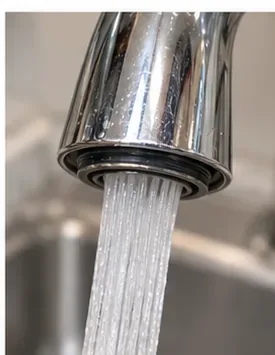 A sink faucet running a straight, even stream after the aerator has been cleaned and reinstalled.