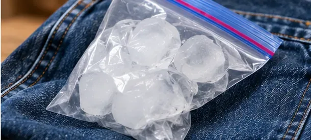 A sealed plastic bag filled with ice resting on blue denim to harden chewing gum before removal