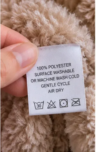 Close-up of a plush teddy bear care label held between two fingers