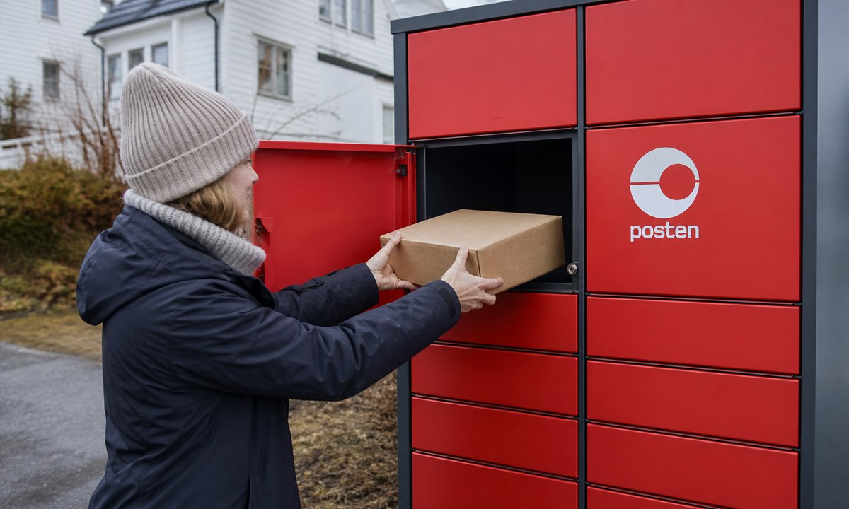 Pakke som plasseres inn i åpen pakkeboks-skuffe av person