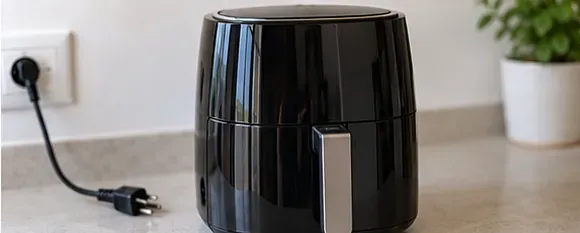 Svart airfryer på kjøkkenbenk med støpselet trukket ut ved siden av apparatet