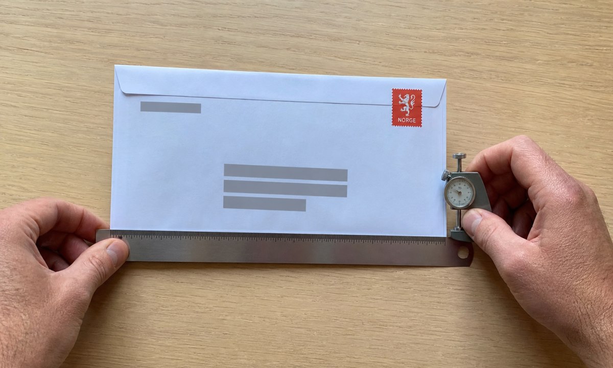 Konvolutt som måles med linjal for å bekrefte at den passer i postkassen